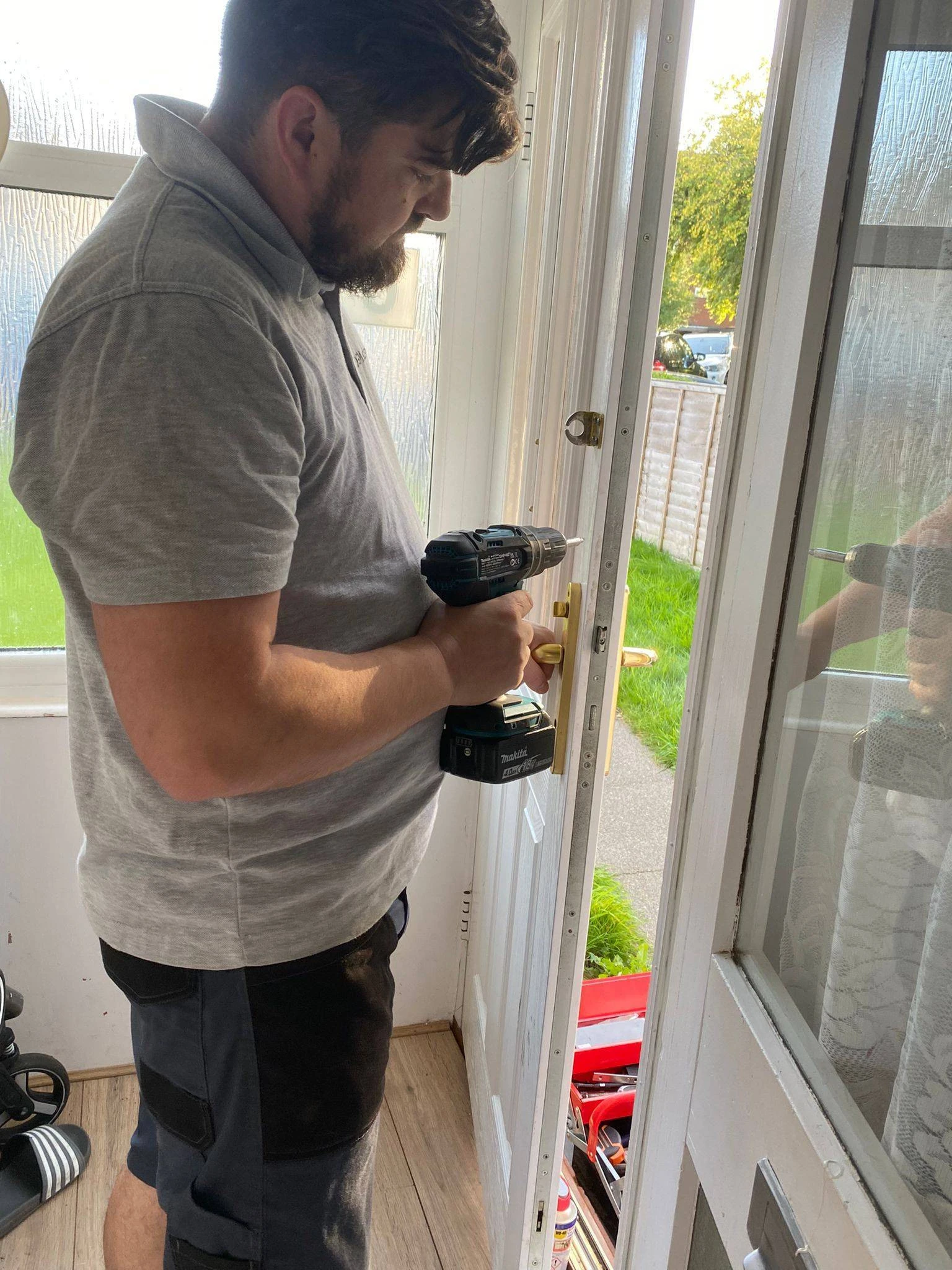 Professional Locksmith using a drill to repair or install a door lock inside a home